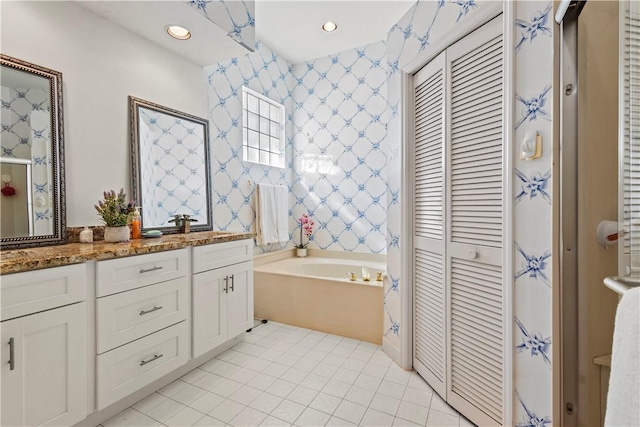 bathroom with a tub to relax in, tile patterned floors, and vanity