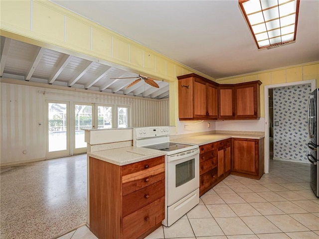 kitchen featuring a peninsula, white electric stove, brown cabinetry, and a ceiling fan