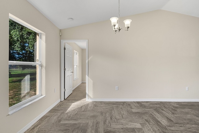 spare room featuring parquet flooring, a healthy amount of sunlight, an inviting chandelier, and vaulted ceiling