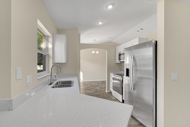 kitchen featuring white cabinetry, appliances with stainless steel finishes, decorative light fixtures, sink, and dark parquet flooring