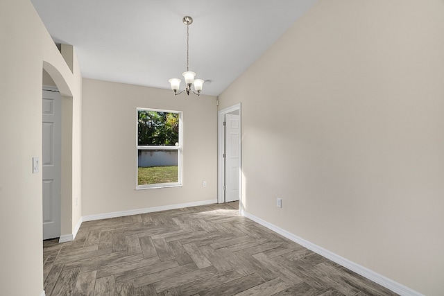 spare room featuring parquet flooring, vaulted ceiling, and an inviting chandelier