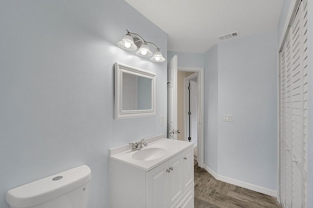 bathroom with toilet, vanity, and parquet flooring