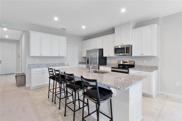 kitchen with white cabinets, appliances with stainless steel finishes, sink, a kitchen breakfast bar, and a kitchen island with sink