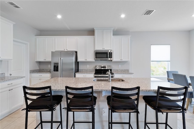 kitchen featuring light stone counters, white cabinets, and stainless steel appliances