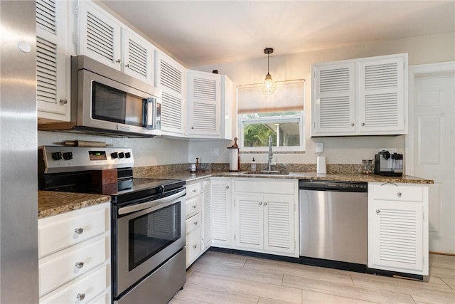 kitchen with sink, decorative light fixtures, white cabinets, and appliances with stainless steel finishes