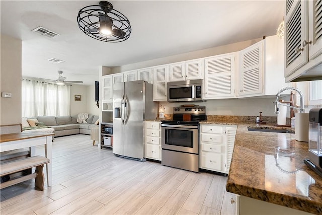 kitchen featuring sink, ceiling fan, appliances with stainless steel finishes, white cabinetry, and decorative light fixtures