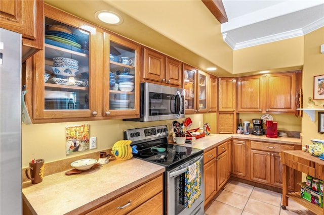 kitchen with light tile patterned floors, crown molding, and stainless steel appliances