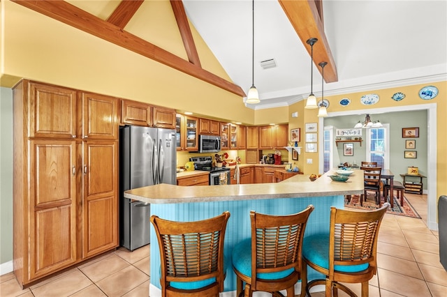 kitchen with decorative light fixtures, light tile patterned floors, a large island with sink, appliances with stainless steel finishes, and beamed ceiling