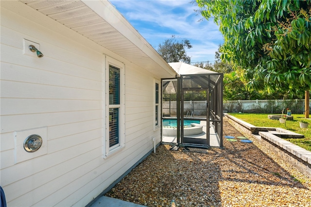 exterior space featuring a fenced in pool and glass enclosure