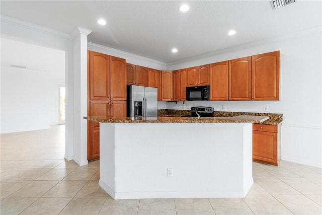 kitchen featuring appliances with stainless steel finishes, a kitchen island with sink, dark stone countertops, ornamental molding, and light tile patterned flooring