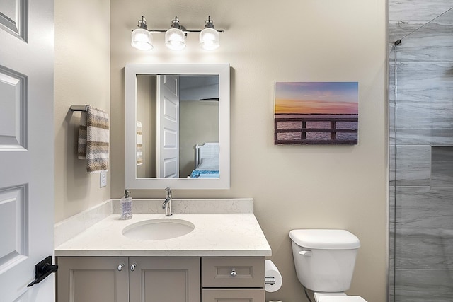 bathroom featuring vanity, toilet, and tiled shower