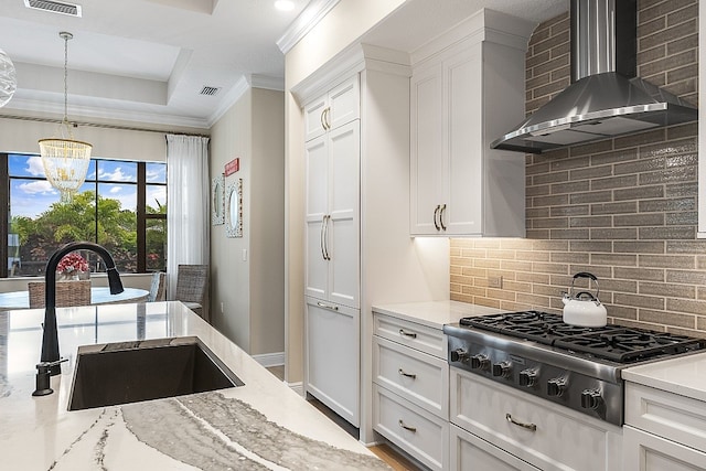 kitchen with stainless steel gas stovetop, white cabinets, sink, wall chimney exhaust hood, and decorative backsplash