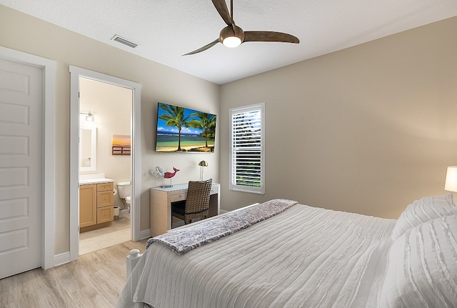 bedroom with a textured ceiling, ensuite bathroom, ceiling fan, and light hardwood / wood-style floors