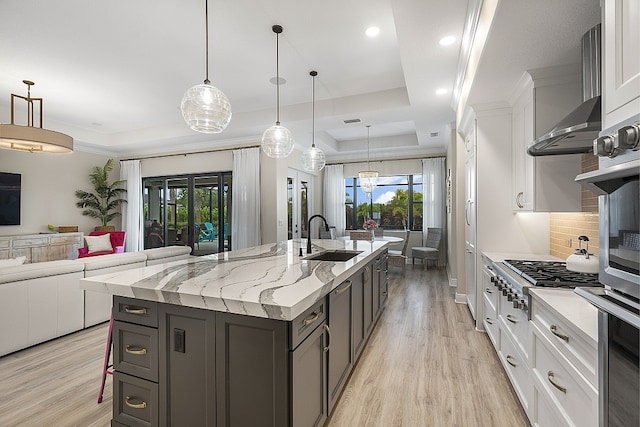 kitchen with a healthy amount of sunlight, sink, white cabinets, and an island with sink