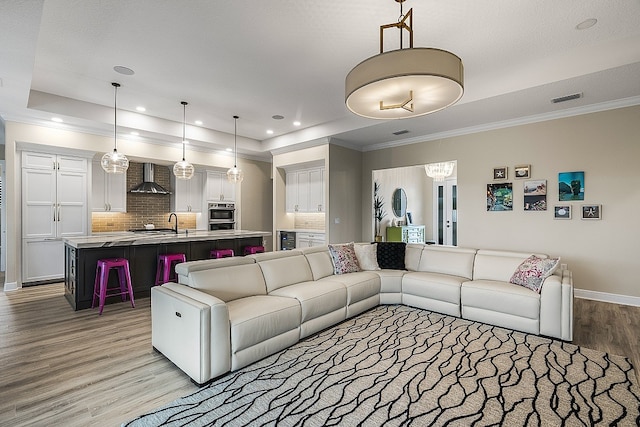 living room with a raised ceiling, light hardwood / wood-style flooring, and ornamental molding