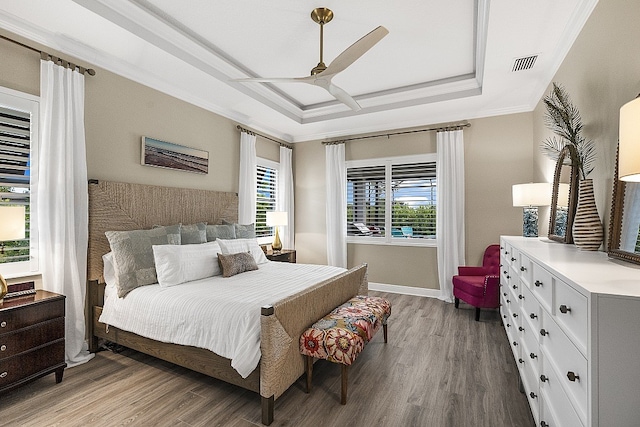 bedroom with hardwood / wood-style floors, ceiling fan, ornamental molding, and a tray ceiling