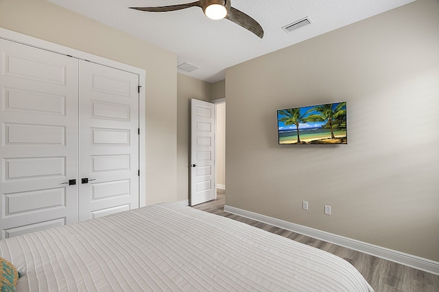 unfurnished bedroom with a textured ceiling, dark hardwood / wood-style flooring, a closet, and ceiling fan