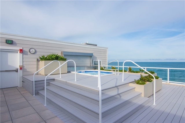 wooden terrace with a hot tub and a water view