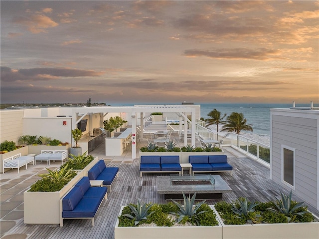 pool at dusk with a water view and an outdoor living space