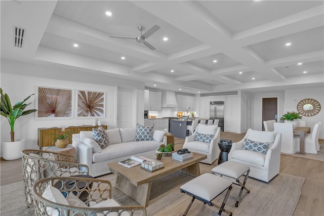 living room with ceiling fan, beam ceiling, light hardwood / wood-style flooring, and coffered ceiling