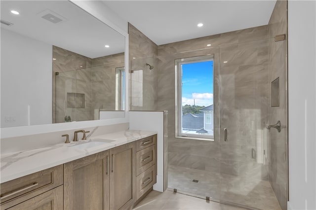 bathroom with walk in shower, vanity, and tile patterned flooring