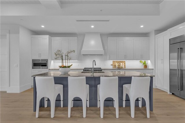 950 Surfsedge Way Unit 205, Vero Beach, FL 32963 - kitchen with premium range hood, appliances with stainless steel finishes, a breakfast bar area, light wood-style flooring, and recessed lighting