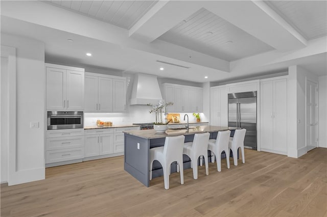 950 Surfsedge Way Unit 205, Vero Beach, FL 32963 - kitchen with appliances with stainless steel finishes, custom exhaust hood, a sink, a breakfast bar area, and light wood-style flooring