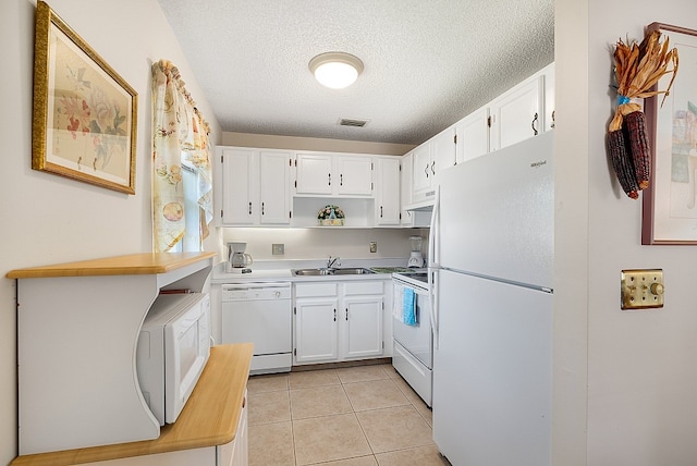 kitchen featuring sink, a textured ceiling, light tile patterned floors, white appliances, and white cabinets