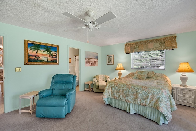 bedroom with a textured ceiling, light colored carpet, ceiling fan, and ensuite bath