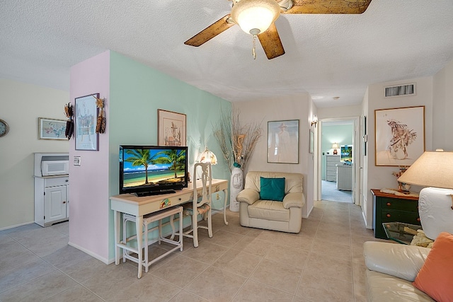 living room with a textured ceiling, ceiling fan, and light tile patterned flooring