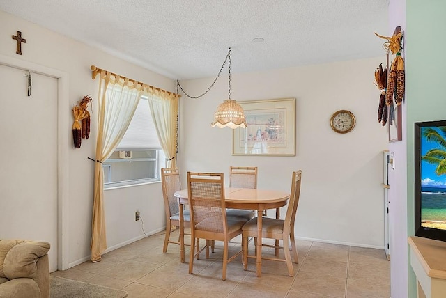 dining room featuring a textured ceiling, light tile patterned floors, and baseboards