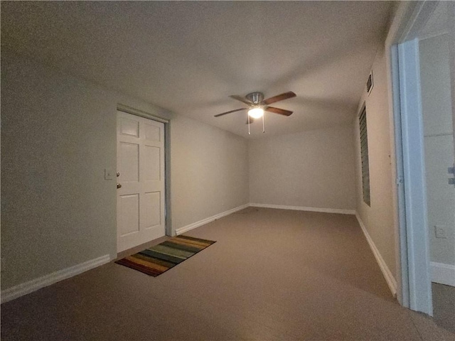 carpeted spare room featuring ceiling fan and baseboards