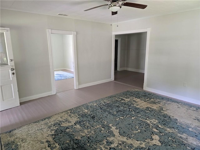 spare room featuring dark wood-style floors, ceiling fan, ornamental molding, and baseboards