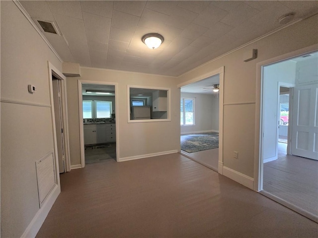 hallway with ornamental molding, wood finished floors, visible vents, and baseboards