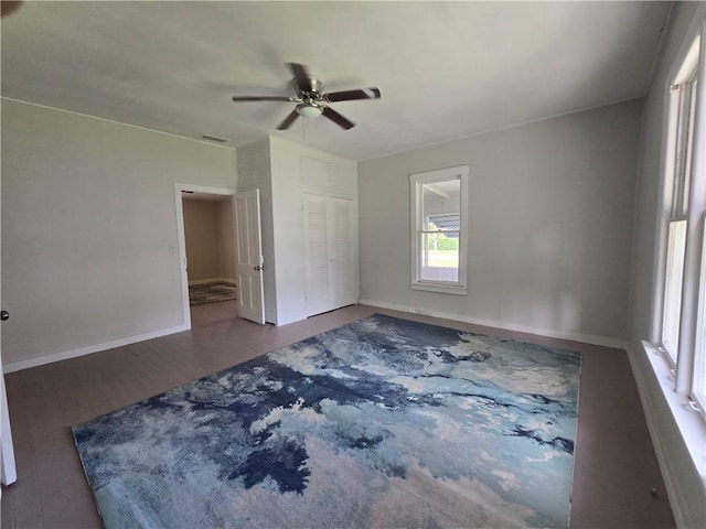 unfurnished room featuring a ceiling fan, wood finished floors, visible vents, and baseboards