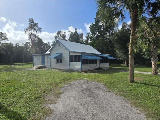 view of side of property featuring driveway and a lawn