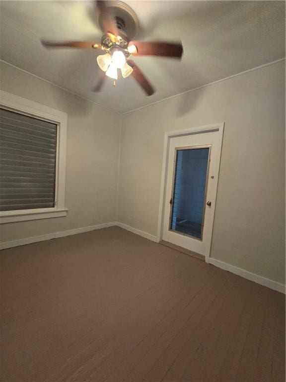 spare room with ceiling fan, baseboards, and dark wood-style flooring