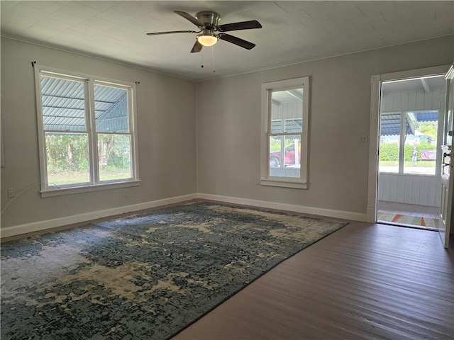 unfurnished room featuring dark wood-style floors, a wealth of natural light, and baseboards