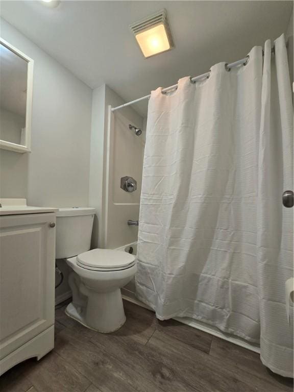 bathroom featuring shower / bath combination with curtain, vanity, toilet, and wood finished floors