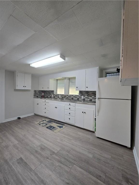 kitchen featuring tasteful backsplash, freestanding refrigerator, and white cabinets