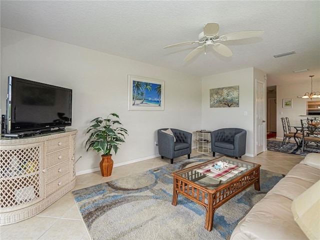 tiled living area featuring baseboards, a textured ceiling, visible vents, and a ceiling fan