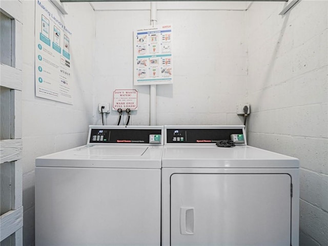 shared laundry area featuring concrete block wall and separate washer and dryer