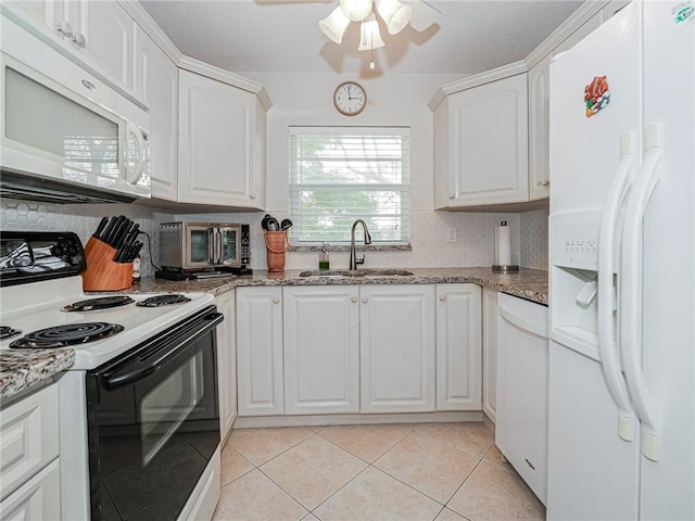 kitchen with white appliances, light tile patterned floors, decorative backsplash, white cabinets, and a sink