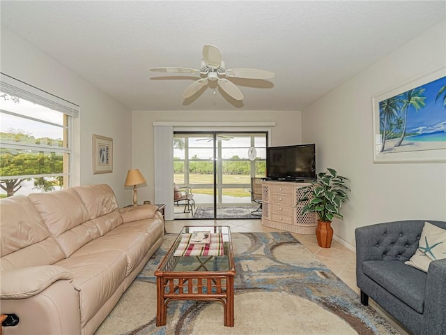 living area with a ceiling fan, plenty of natural light, and light tile patterned floors