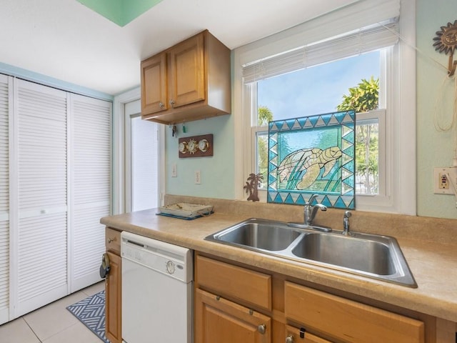 kitchen with a healthy amount of sunlight, light tile patterned flooring, white dishwasher, and sink