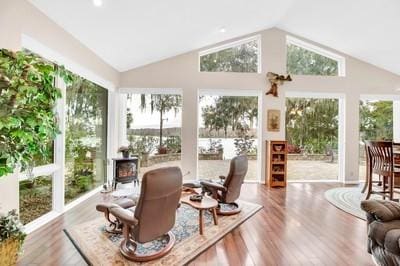 sunroom / solarium featuring vaulted ceiling and a wood stove