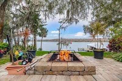 view of patio with a dock, a water view, and an outdoor fire pit