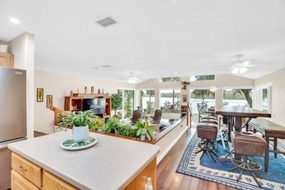 kitchen with hardwood / wood-style floors, light brown cabinetry, stainless steel refrigerator, a center island, and ceiling fan