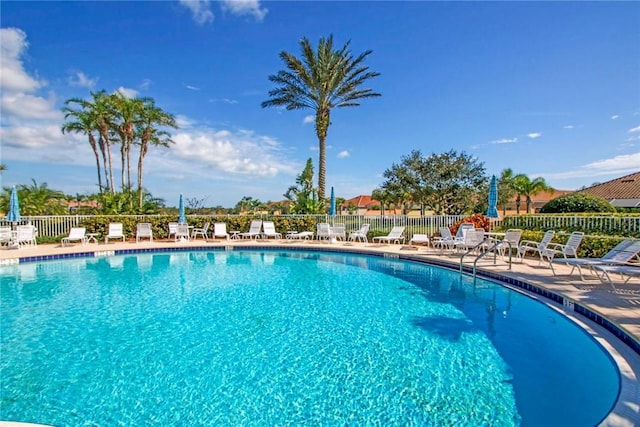 community pool with a patio area and fence