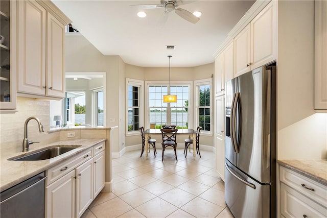 kitchen featuring decorative light fixtures, ceiling fan, sink, appliances with stainless steel finishes, and light stone counters